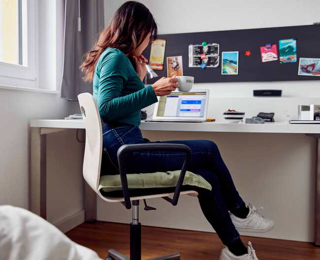 Studentin sitzt am Schreibtisch in ihrem Studentenappartment